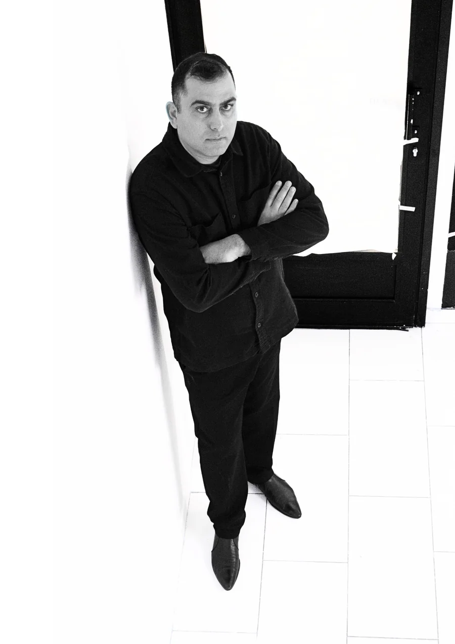 Portrait of artist Eran Amar Shookroon beside a black doorway